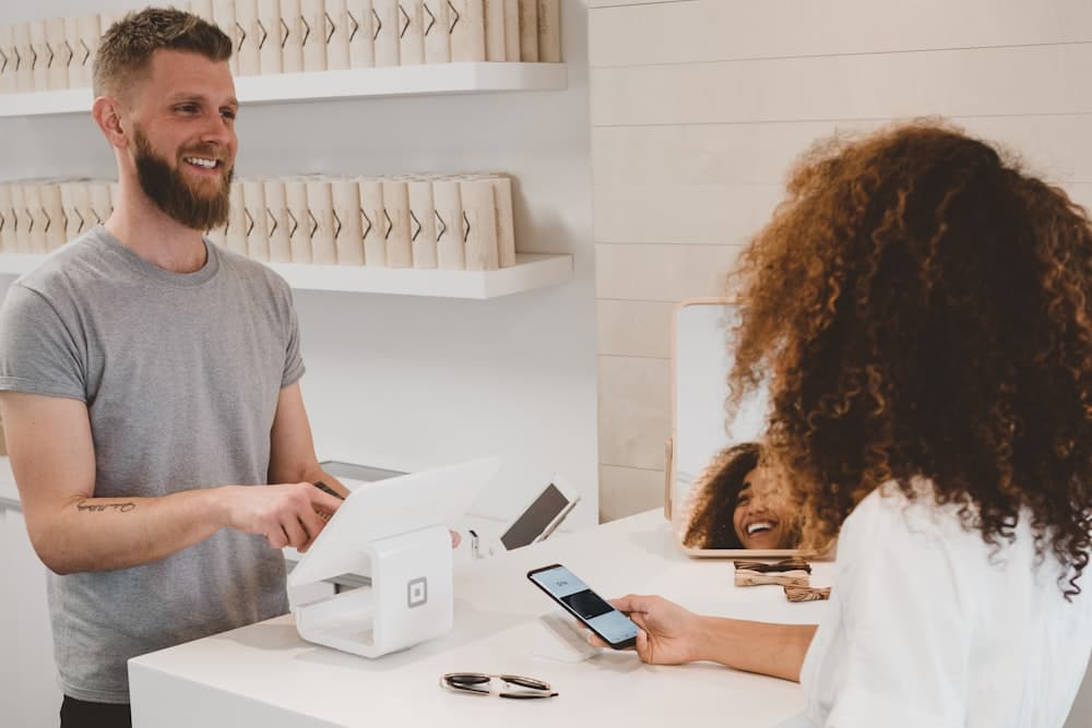 Two people sharing a phone at a warm, sunny shop